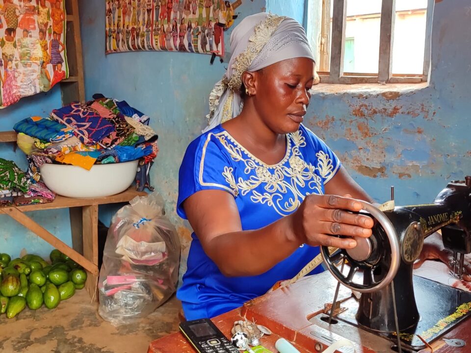 Ramatou assise sur sa machine à coudre